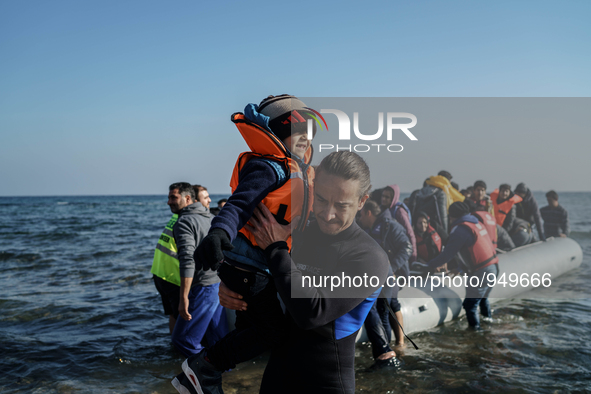 Volunteers help around 50 refugees and migrants to disembark from a vessel after their arrival from the Turkish coast to the northeastern Gr...