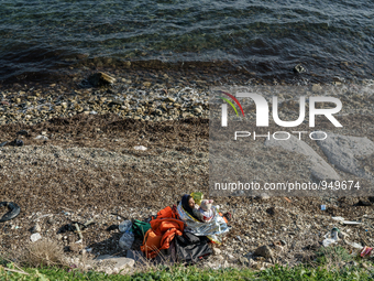 A women holds her child on a beach near to the town of Mytilene after crossing a part of the Aegean sea on a dinghy, with other refugees and...