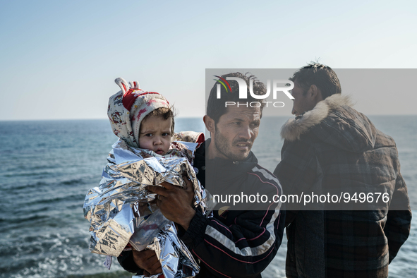 A man holds her child on a beach near to the town of Mytilene after crossing a part of the Aegean sea on a dinghy, with other refugees and m...