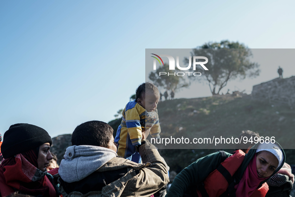 Brother holds up a baby as others help migrants and refugees to disembark from a dinghy after their arrival from the Turkish coast to the Gr...