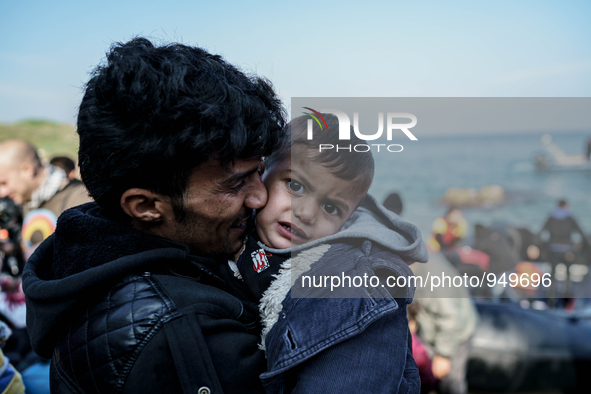 A man holds her child on a beach near to the town of Mytilene after crossing a part of the Aegean sea on a dinghy, with other refugees and m...