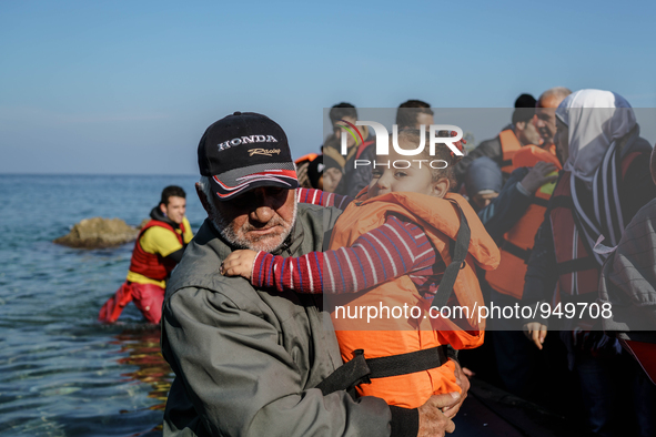 A man holds her child on a beach near to the town of Mytilene after crossing a part of the Aegean sea on a dinghy, with other refugees and m...