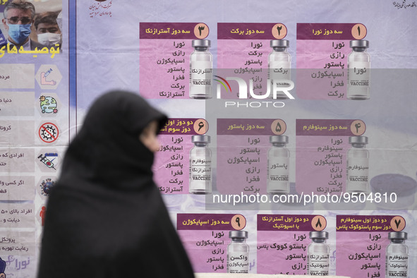 A veiled Iranian worshipper stands in front of a banner with Images of new coronavirus disease (COVID-19) vaccines, hanged on a mobile vacci...