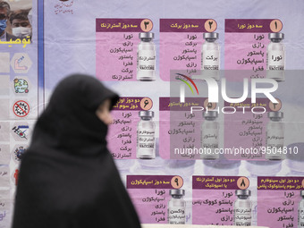 A veiled Iranian worshipper stands in front of a banner with Images of new coronavirus disease (COVID-19) vaccines, hanged on a mobile vacci...