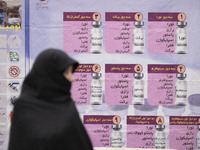 A veiled Iranian worshipper stands in front of a banner with Images of new coronavirus disease (COVID-19) vaccines, hanged on a mobile vacci...