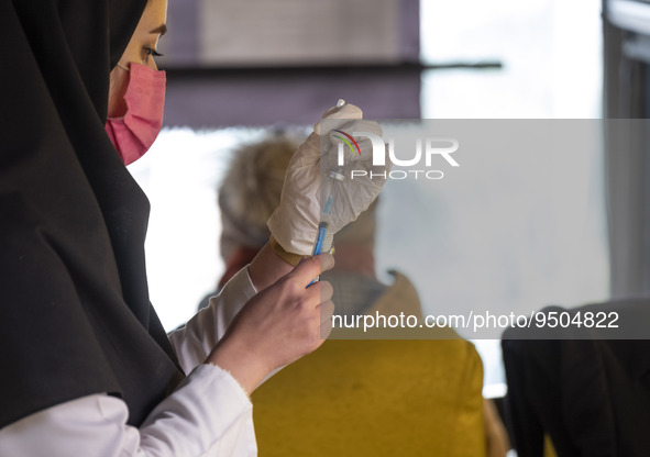 An Iranian female health personnel wearing a protective face mask loads a syringe with the Iranian Noora new coronavirus disease (COVID-19)...