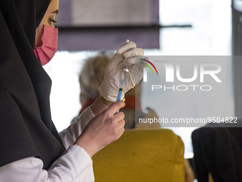 An Iranian female health personnel wearing a protective face mask loads a syringe with the Iranian Noora new coronavirus disease (COVID-19)...