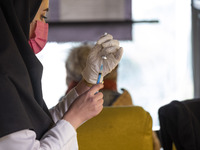 An Iranian female health personnel wearing a protective face mask loads a syringe with the Iranian Noora new coronavirus disease (COVID-19)...