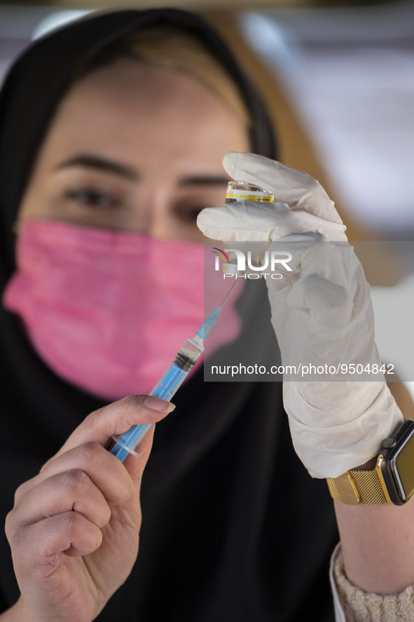 An Iranian female health personnel wearing a protective face mask loads a syringe with the Iranian Noora new coronavirus disease (COVID-19)...