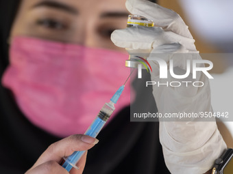 An Iranian female health personnel wearing a protective face mask loads a syringe with the Iranian Noora new coronavirus disease (COVID-19)...