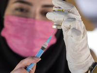 An Iranian female health personnel wearing a protective face mask loads a syringe with the Iranian Noora new coronavirus disease (COVID-19)...