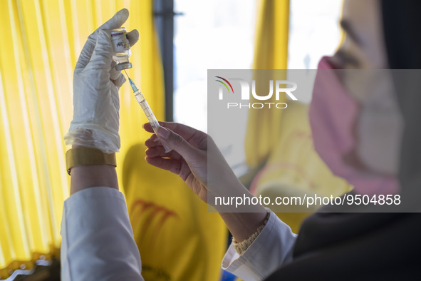 An Iranian female health personnel wearing a protective face mask loads a syringe with the Iranian Noora new coronavirus disease (COVID-19)...