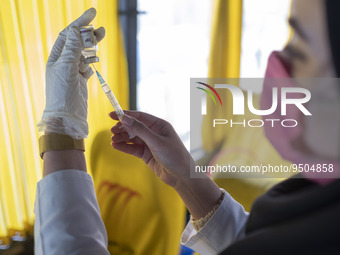 An Iranian female health personnel wearing a protective face mask loads a syringe with the Iranian Noora new coronavirus disease (COVID-19)...