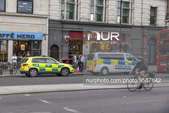 Yellow ambulance, an emergency service vehicle with paramedics of the National Health Service NHS parked behind a police car on the streets...