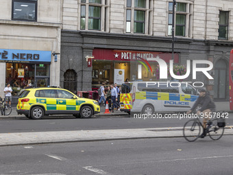 Yellow ambulance, an emergency service vehicle with paramedics of the National Health Service NHS parked behind a police car on the streets...