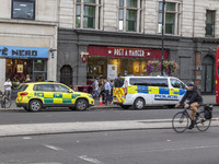 Yellow ambulance, an emergency service vehicle with paramedics of the National Health Service NHS parked behind a police car on the streets...