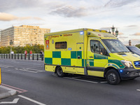 Yellow ambulance spotted on Westminster Bridge, an emergency service vehicle with paramedics of the National Health Service NHS in motion on...