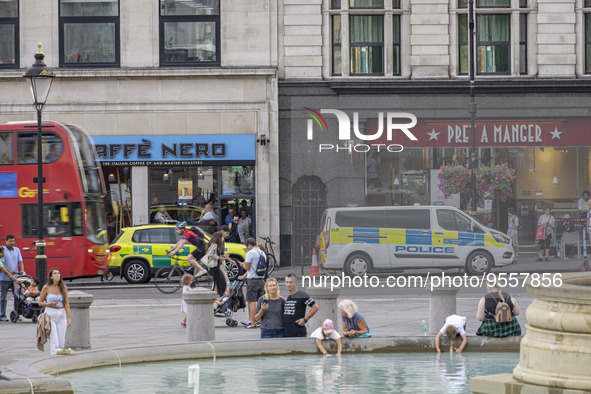 Yellow ambulance, an emergency service vehicle with paramedics of the National Health Service NHS parked behind a police car on the streets...