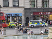 Yellow ambulance, an emergency service vehicle with paramedics of the National Health Service NHS parked behind a police car on the streets...