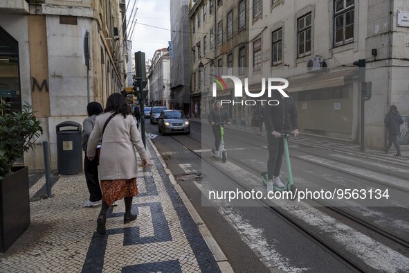 People riding scooters are seen crossing along one of the streets in the Baixa district. Lisbon, January 23, 2023. In Portugal, the transmis...