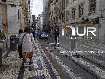 People riding scooters are seen crossing along one of the streets in the Baixa district. Lisbon, January 23, 2023. In Portugal, the transmis...