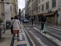 People riding scooters are seen crossing along one of the streets in the Baixa district. Lisbon, January 23, 2023. In Portugal, the transmis...