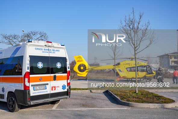 Ambulance and Medical helicopter landed in the background in a public car parking , in Cernusco sul Naviglio, Italy, on February 10, 2023.  