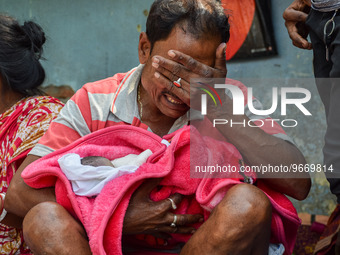 A man cries as he holds the body of his three-day-old grandson who died from respiratory problems, at a hospital in Kolkata, on March 01, 20...