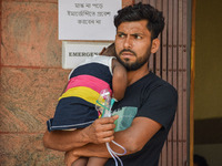 A man holds his daughter who is suffering from respiratory problems, ahead of her health check-up, at a hospital in Kolkata, on March 01, 20...