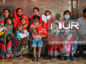 Women wait in queue as they have come for a health check-up of their children, who are suffering from fever and respiratory problems, at a h...