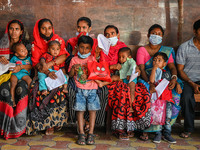 Women wait in queue as they have come for a health check-up of their children, who are suffering from fever and respiratory problems, at a h...