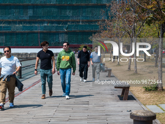 Unmasked men stroll on the Kwun Tong Promenade around noon. Today was the first day the mask mandate was abolished in Hong Kong after 950 da...