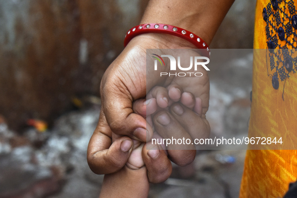 A woman is holding the hand of her child and standing in the queue waiting for treatment as the child has suffered from fever and respirator...