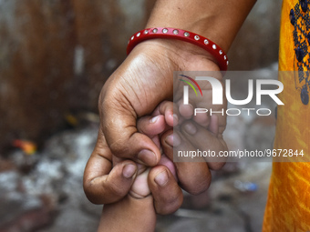 A woman is holding the hand of her child and standing in the queue waiting for treatment as the child has suffered from fever and respirator...