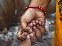 A woman is holding the hand of her child and standing in the queue waiting for treatment as the child has suffered from fever and respirator...