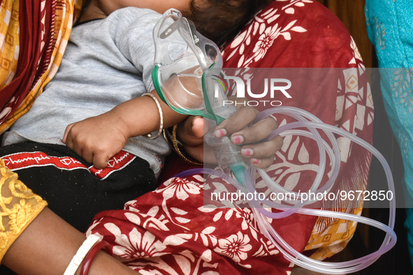 A woman is holding an Oxygen mask and waiting for treatment for her child outside an Emergency ward in a government-run hospital for sufferi...