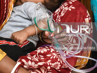 A woman is holding an Oxygen mask and waiting for treatment for her child outside an Emergency ward in a government-run hospital for sufferi...