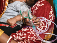 A woman is holding an Oxygen mask and waiting for treatment for her child outside an Emergency ward in a government-run hospital for sufferi...