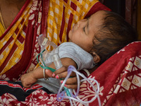 A woman holds the nebulizer mask of her child who is suffering from respiratory problems, at a hospital in Kolkata, on March 02, 2023. The e...