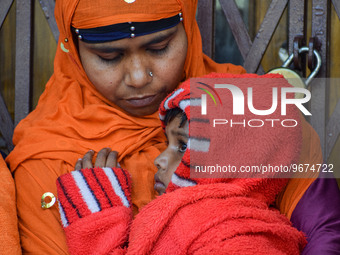 A woman holds her five-year-old daughter, who is suffering from respiratory problems, ahead of her health check-up, at a hospital in Kolkata...