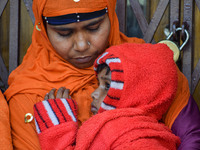 A woman holds her five-year-old daughter, who is suffering from respiratory problems, ahead of her health check-up, at a hospital in Kolkata...