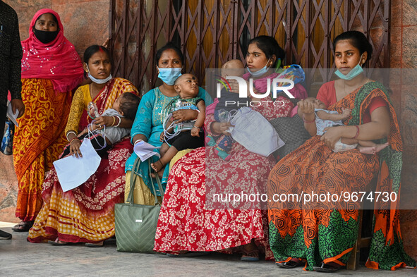 Women wait in queue as they have come for a health check-up of their children, who are suffering from respiratory problems, at a hospital in...