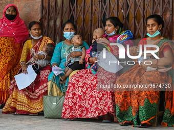 Women wait in queue as they have come for a health check-up of their children, who are suffering from respiratory problems, at a hospital in...