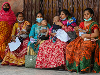 Women wait in queue as they have come for a health check-up of their children, who are suffering from respiratory problems, at a hospital in...