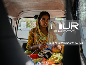 A woman holds the nebulizer mask of her child, who is suffering from respiratory problems, inside an ambulance, at a hospital in Kolkata, on...