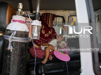 A woman sits inside an ambulance with her child, who is suffering from respiratory problems, at a hospital in Kolkata, on March 02, 2023. Th...