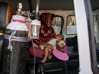 A woman sits inside an ambulance with her child, who is suffering from respiratory problems, at a hospital in Kolkata, on March 02, 2023. Th...