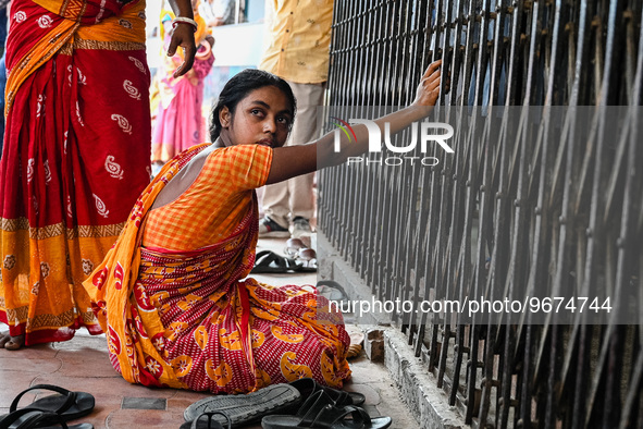 A woman sits in front of the gate of a hospital building, where her three-year-old daughter is undergoing treatment for respiratory problems...