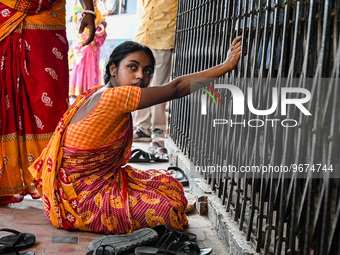 A woman sits in front of the gate of a hospital building, where her three-year-old daughter is undergoing treatment for respiratory problems...