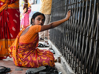 A woman sits in front of the gate of a hospital building, where her three-year-old daughter is undergoing treatment for respiratory problems...